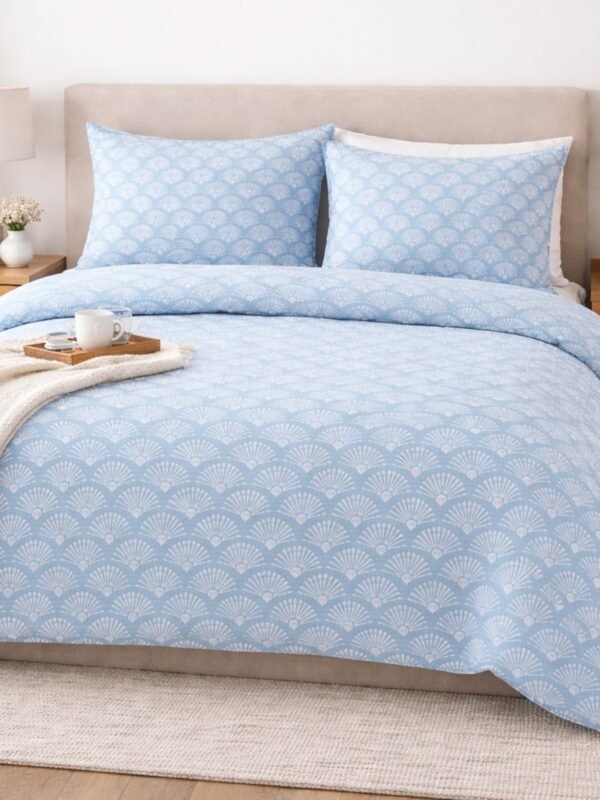 Blue printed double bed bedsheet with elegant fan pattern styled on a bed creating modern bedroom decor.